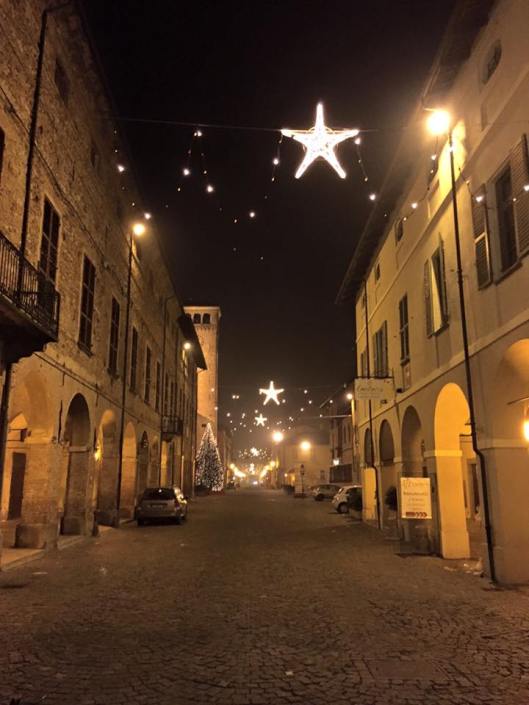 Cherasco, atmosfera natalizia in via Vittorio Emanuele II, in direzione dell'arco di Porta Narzole, con a sinistra la torre del municipio, e a destra lo storico Palazzo Mentone (foto di Bianca Prando)